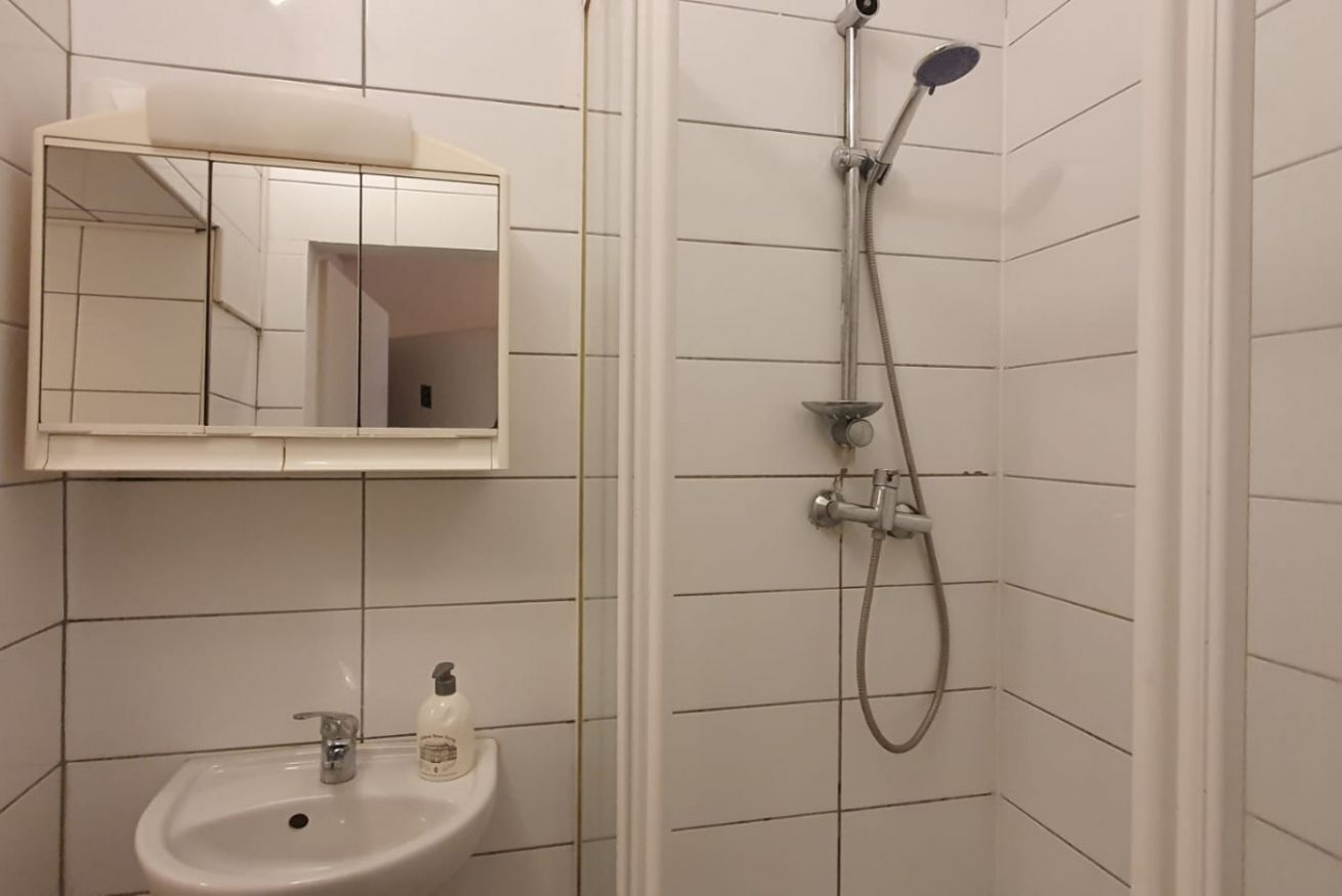Un bany amb un lavabo blanc, un mirall i una dutxa.