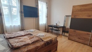Ein Schlafzimmer mit Bett, Schreibtisch, Stuhl, Fernseher und Kleiderschrank.