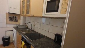 Eine Küche mit Mikrowelle, Spüle und Waschmaschine.