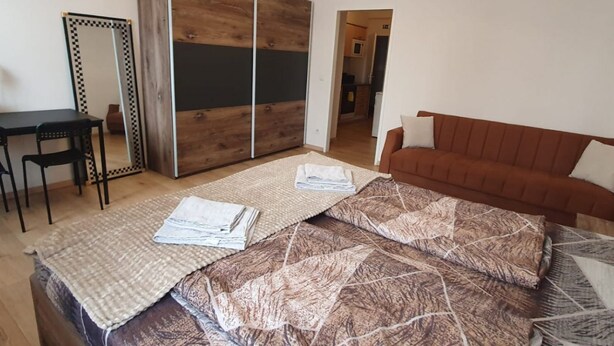Ein Schlafzimmer mit Bett, Sofa, Schreibtisch und Kleiderschrank.