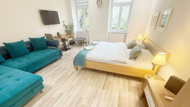 A bedroom with a bed, a sofa, a desk, a chair, and a TV. - Chic 1BR Apt Near Biggest Amusementpark of Vienna (Vienna)