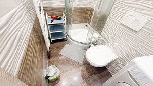 A bathroom with a shower, toilet, and a towel rack. - Chic 1BR Apt Near Biggest Amusementpark of Vienna (Vienna)