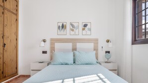 A bedroom with a bed, two bedside tables, a nightstand, a wooden wardrobe, and three framed artworks on the wall. - Holiday Home 'Villa' with Private Pool, Wi-Fi and Air Conditioning (Conil de la Frontera)