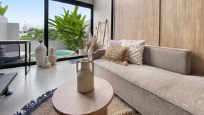 A modern living room with a sofa, a coffee table, and a view of a swimming pool. - Brand New Private Pool Villa (canggu)