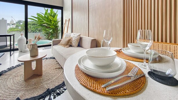 A modern dining area with a round table set for two, featuring white plates, bowls, and cutlery. - Brand New Private Pool Villa (canggu)