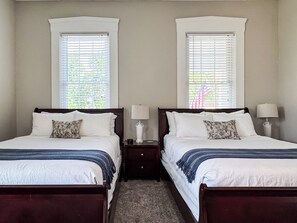 A double room with two beds, each with a nightstand, a lamp, and a window with blinds. - Aussie Cottage | Dog-friendly, Fire pit, Fenced yard (Washington)