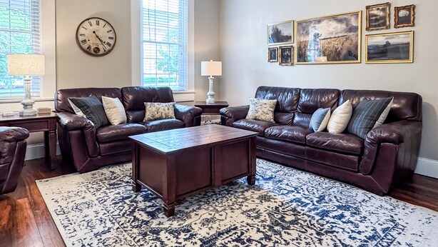 A living room with two leather sofas, a coffee table, and a patterned rug.