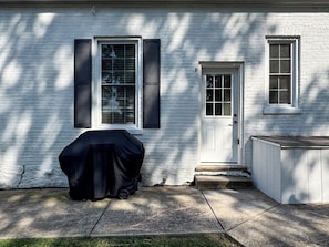 A white brick house with a covered grill, a white door, and a small porch. - Mini Aussie | Dog-friendly, Fire pit, Fenced yard (Washington)