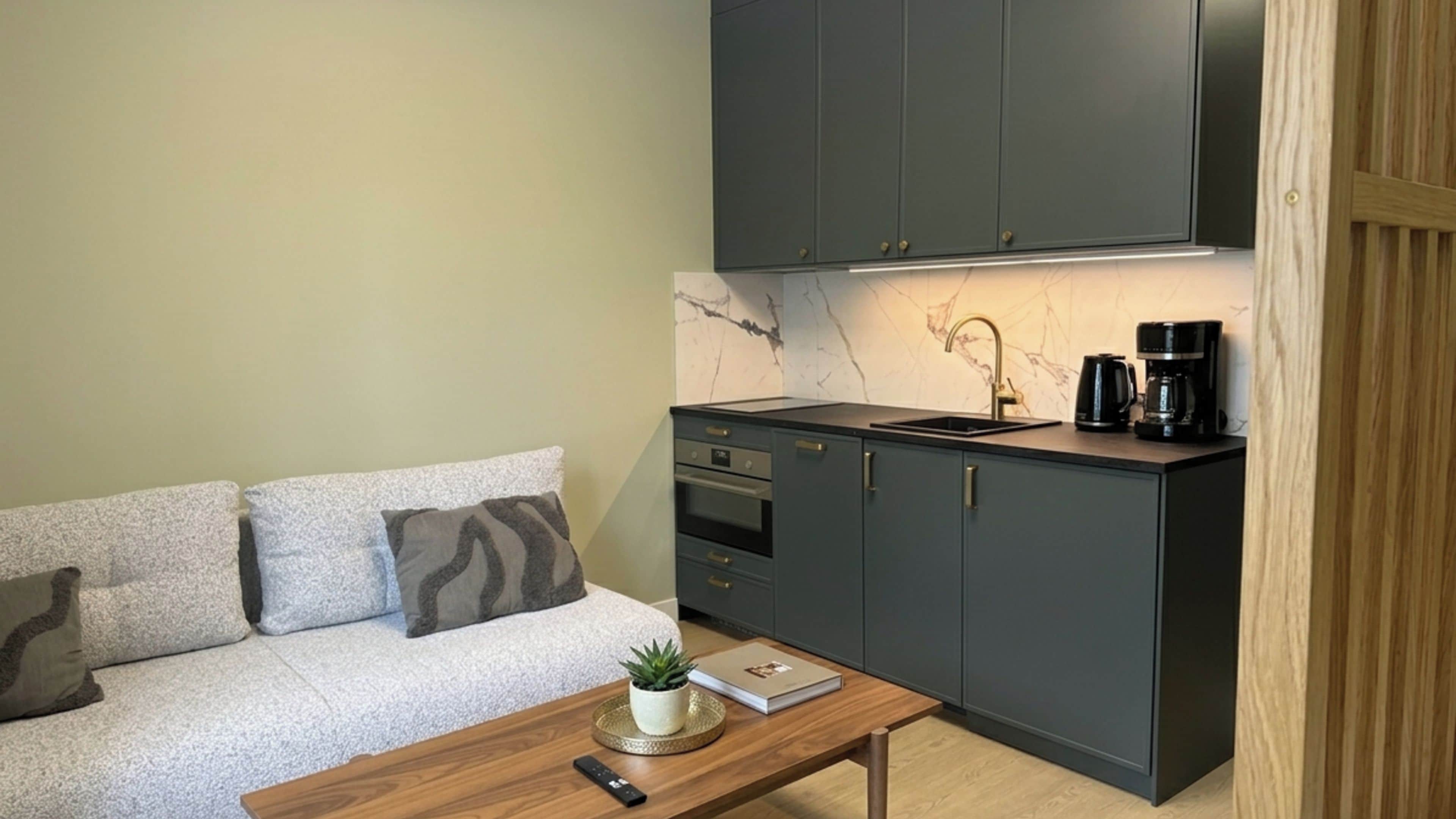A compact kitchenette with a built-in oven, a sink, and a coffee maker.