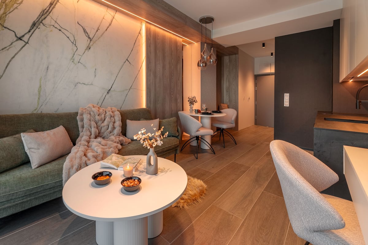 A modern living room with a sofa, a round coffee table, and a dining area with chairs.