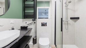 A modern bathroom with a white sink, black countertop, and a glass shower enclosure. - Sun & Snow Willa Zieleniec (Duszniki Zdroj)