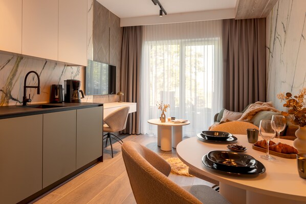 A modern kitchen with a marble backsplash, a dining area with a round table, and a cozy seating area with a sofa and a coffee table. - Sun & Snow Willa Zieleniec (Duszniki Zdroj)