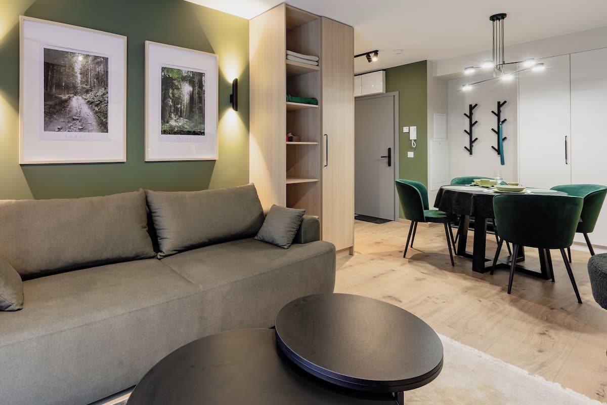 A modern living room with a sofa, a dining table with chairs, and two framed pictures on the wall.