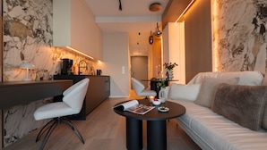 A modern living room with a sofa, a dining table, and a kitchen area. - Apartamenty Sun & Snow Willa Zieleniec (Duszniki Zdroj)