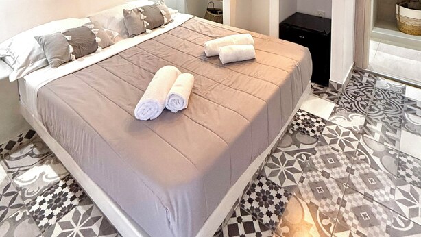 Un dormitorio moderno con una cama grande, televisión y estantería.