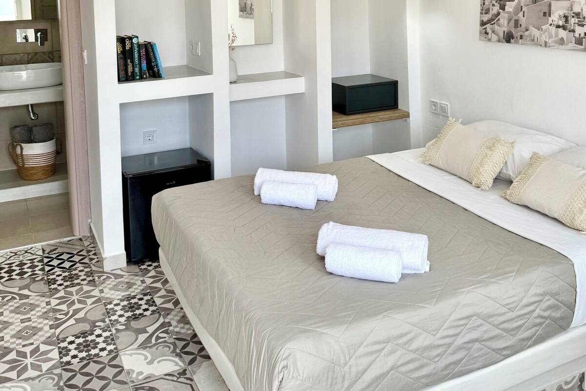 Une chambre moderne avec un lit, des tables de chevet, un miroir et un téléviseur fixé au mur.