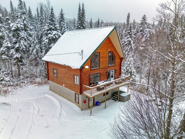 A wooden cabin with a balcony, surrounded by snow-covered trees.