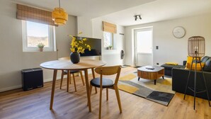 Ein modernes Wohnzimmer mit einem runden Holztisch, zwei Stühlen, einem Sofa, einem Couchtisch und einer Stehlampe.