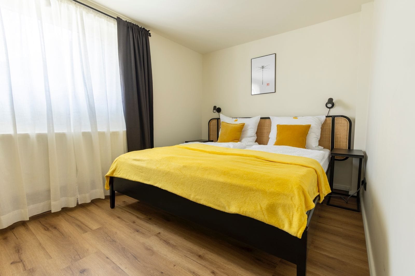 Un dormitorio con una cama, una mesita de noche, una lámpara y una ventana con cortinas.