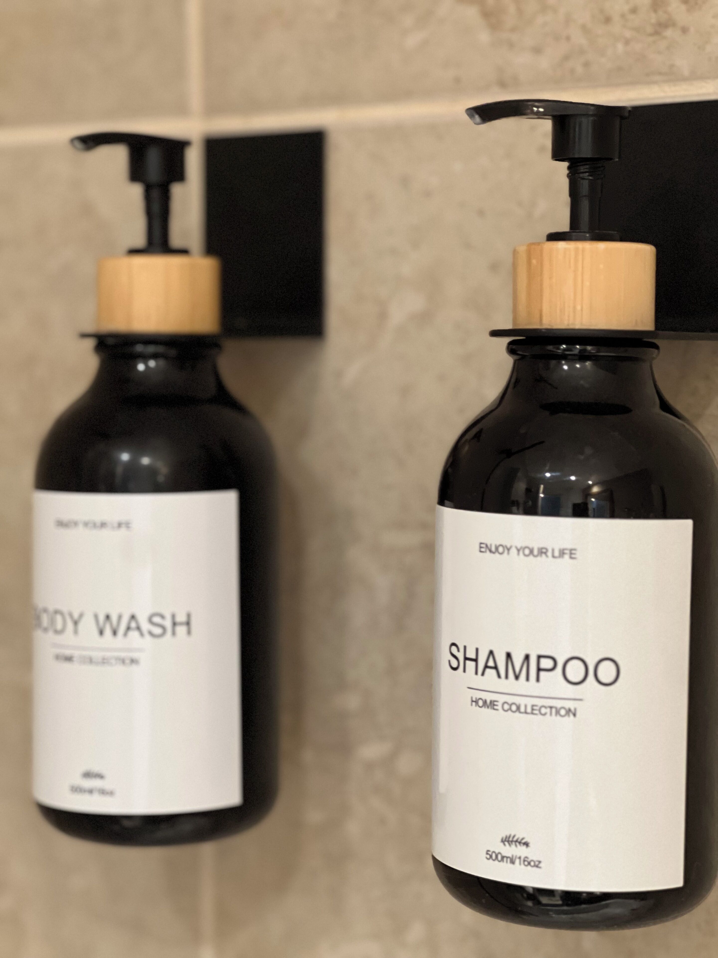 Two bottles of body wash and shampoo with pump dispensers, labeled 'BODY WASH' and 'SHAMPOO', respectively, in a bathroom setting.
