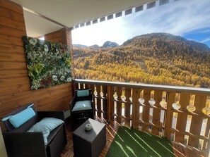 A balcony with wicker furniture, a green artificial turf, and a view of a forested mountain range. - Spectacular 6-person apartment in the center, near the slopes and shops (Isola)