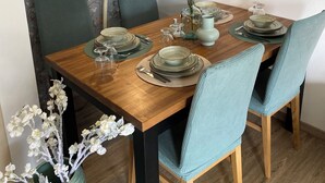 Een eettafel gedekt met borden, glazen en een bloevas.