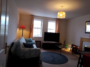 A living room with a sofa, TV, and a fireplace. - The Longchamp Retreat of Ely (Ely)