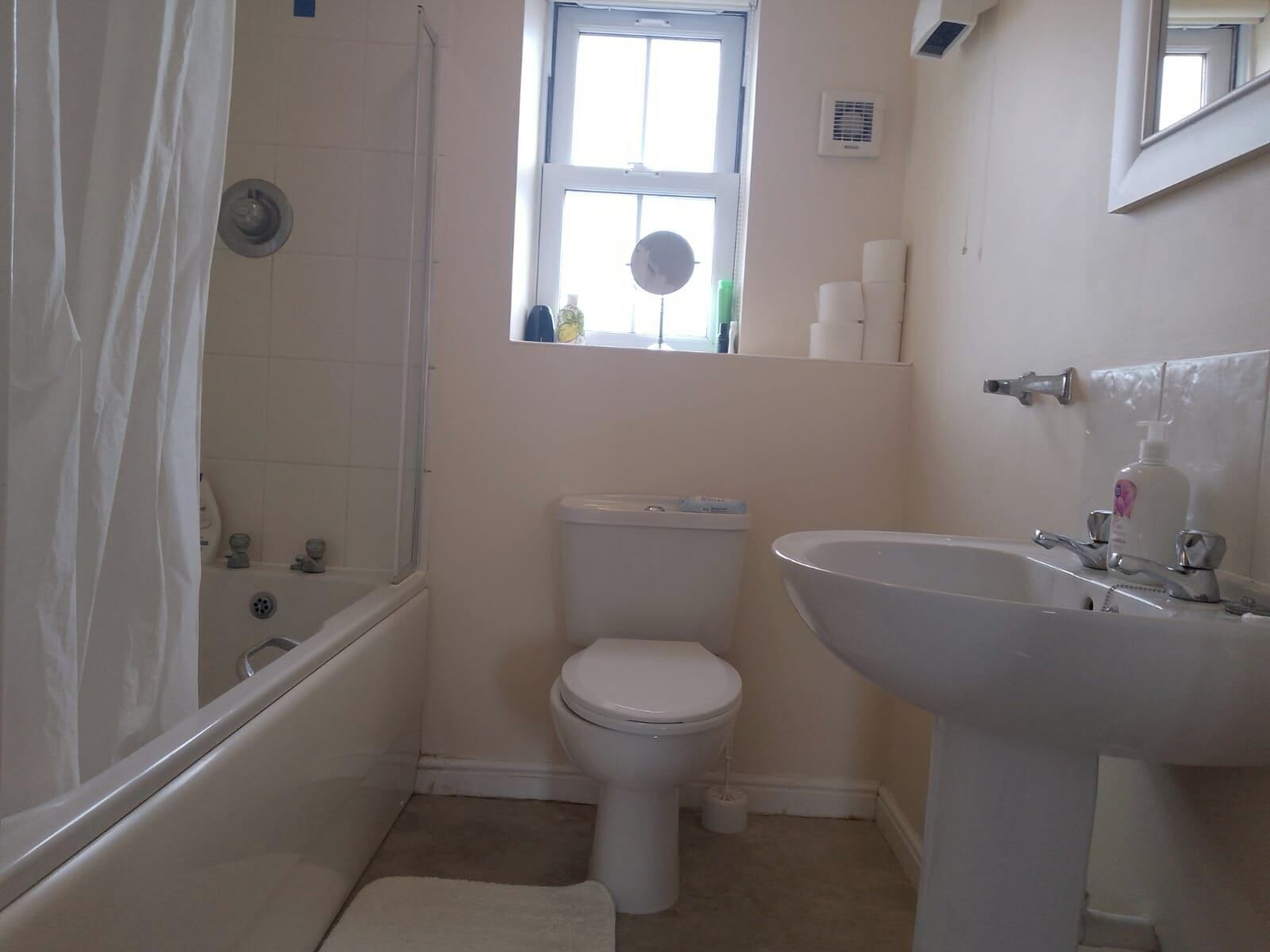 Une petite salle de bain simple, équipée de toilettes, d’un lavabo et d’une douche.