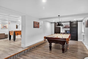 Una sala de estar moderna con mesa de billar, mesa de futbolín y un espacio de descanso acogedor.