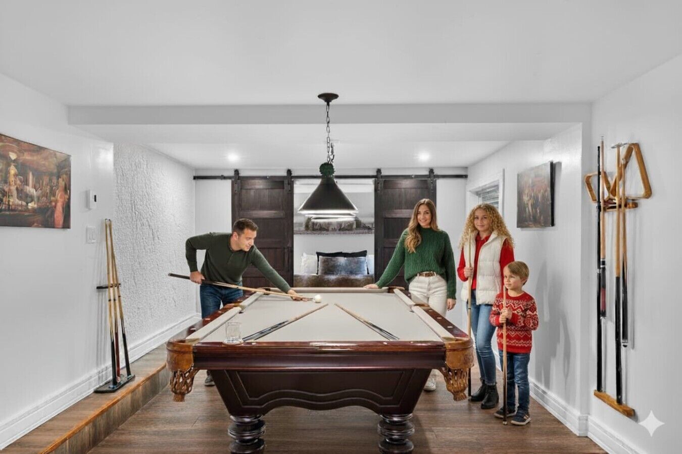 Une pièce avec une table de billard, un lustre et des tableaux aux murs.