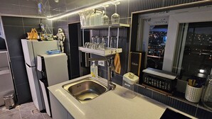 Een moderne keuken met een spoelbak, een koelkast en een raam met uitzicht op een stadsgezicht.