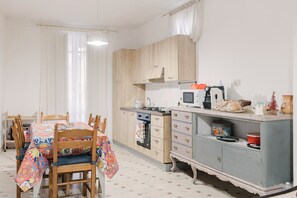 Una cocina con armarios de madera, una mesa de comedor con sillas y un microondas.