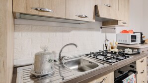 Une cuisine avec des armoires en bois, un évier en acier inoxydable, une cuisinière à gaz et un four à micro-ondes.