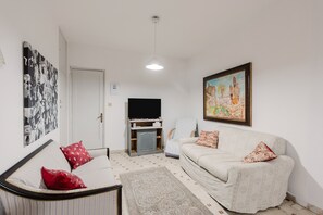 Una sala de estar con sofá, televisión, sillón y alfombra.