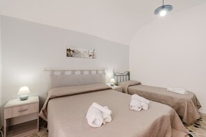 Una habitación de hotel con dos camas, una mesita de noche con una lámpara y un cuadro en la pared.