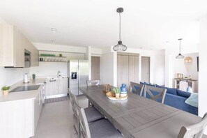 Una cocina moderna con comedor, refrigerador y una lámpara colgante.