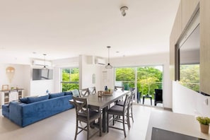 Ein modernes Wohnzimmer mit Essbereich, großen Fenstern und Blick ins Grüne.