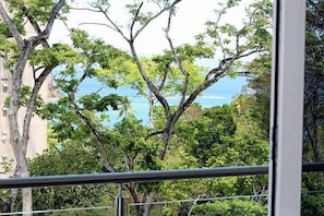 A balcony with a view of trees and a distant body of water.
