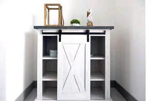Una puerta corredera de estilo granero blanca con un tirador negro, una planta pequeña y un marco de madera sobre un gabinete blanco con varios estantes.