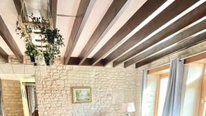 Un salon avec un mur en pierre, un canapé, un fauteuil et une table basse.
