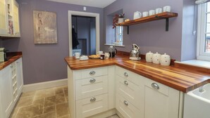 A kitchen with white cabinetry, a wooden countertop, and a window with a view. - Daleholme (Barnard Castle)