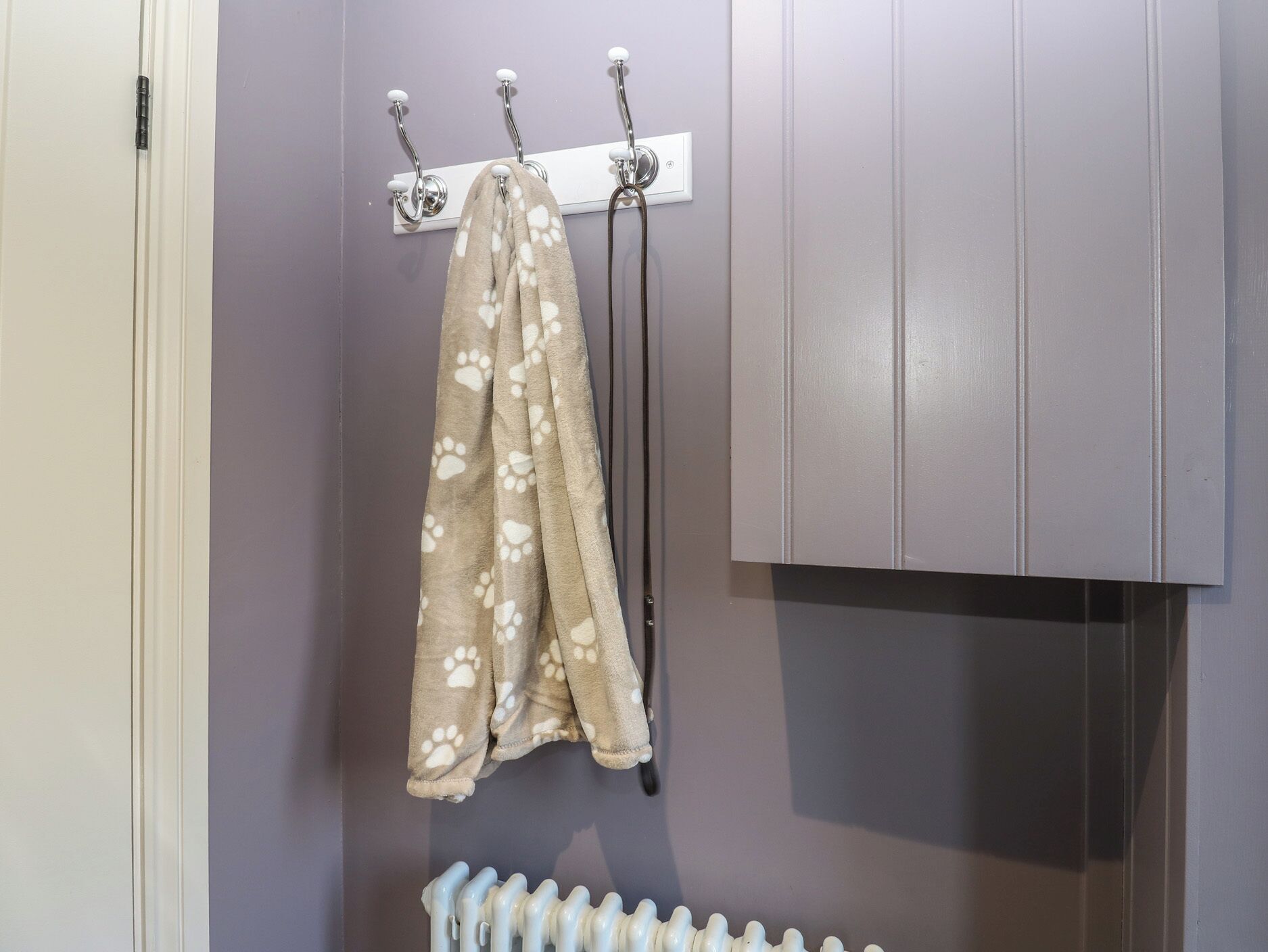 Een badkamer met een handdoekrek, waarop een handdoek met pootafdrukken ligt, een radiator en een deur.