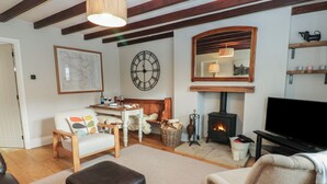 A cozy living room with a fireplace, a clock, and a television. - Daleholme (Barnard Castle)