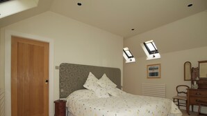 A bedroom with a bed, dresser, and a door. - Cosy Cottage set in lovely gardens, 2 miles east of the seaside town of Nairn (Auldearn)
