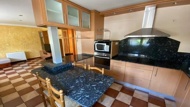 Una cocina con piso a cuadros, encimera de mármol, gabinetes de madera, microondas y estufa.