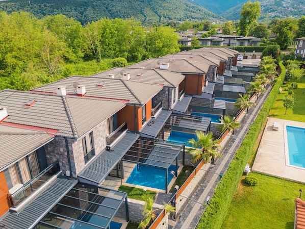 A resort with modern villas, swimming pools, and a lush green landscape.