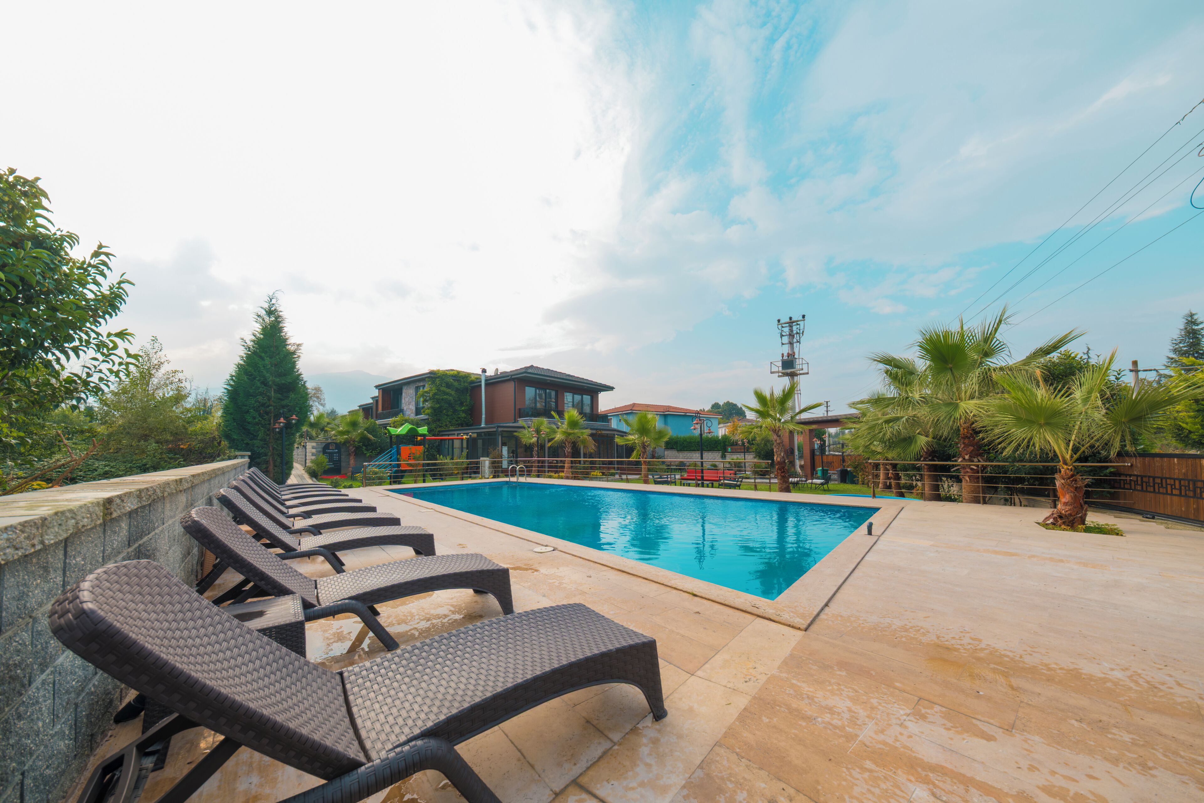 A swimming pool with lounge chairs, a stone deck, and a view of buildings in the background.