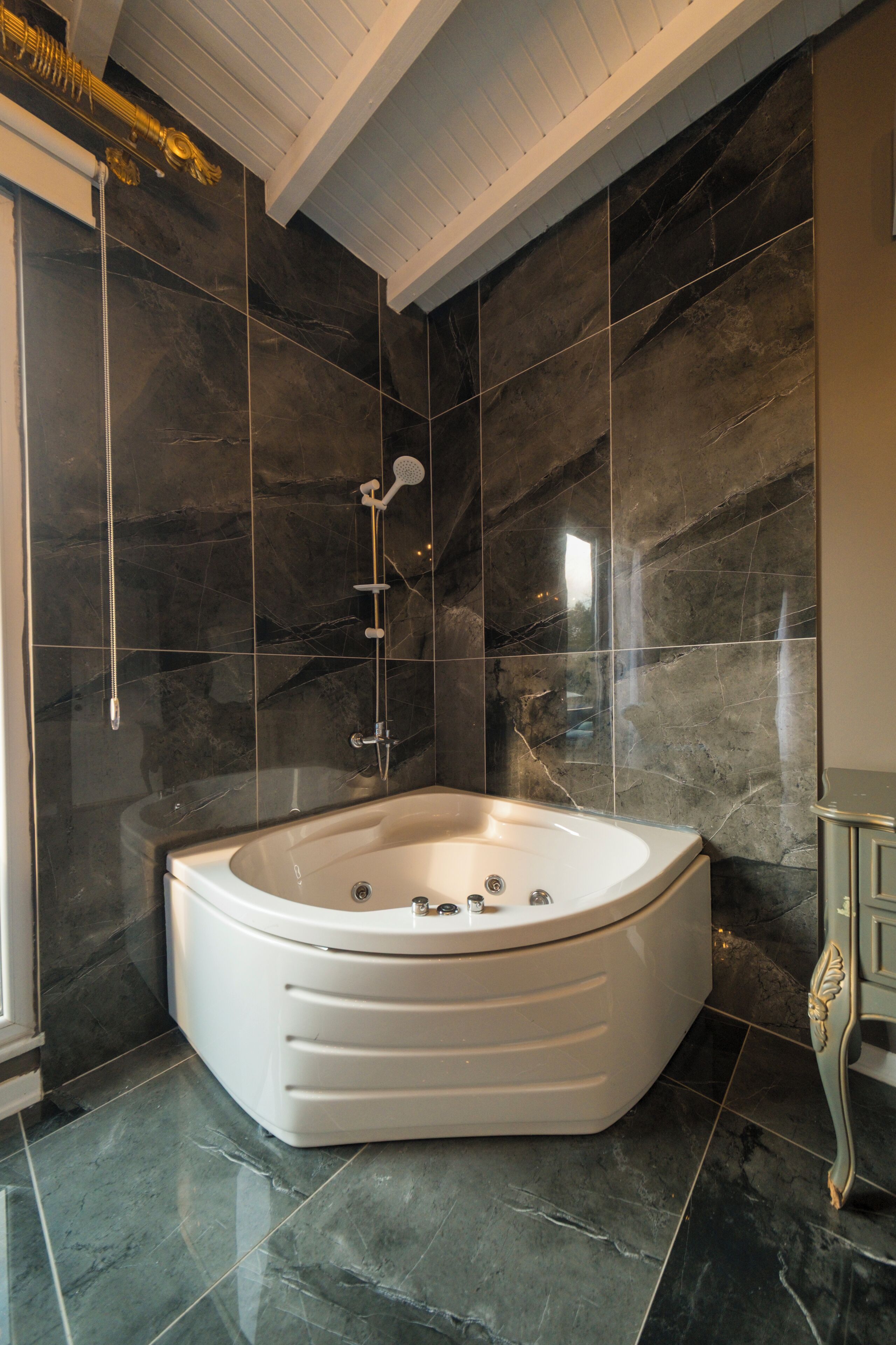 Une salle de bain moderne avec une baignoire sur pieds, des murs en marbre foncé et un plafond blanc.