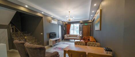 Una sala de estar moderna con un sofá, sillas, una mesa de comedor y una escalera.