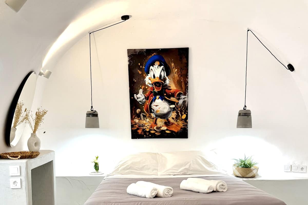 A modern bedroom with a large bed, marble flooring, and a wall-mounted artwork of a cartoon character.